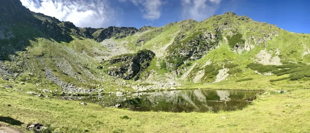 Munții Carpați din România sunt unul dintre cele mai mari comori naturale ale țării. Aceștia oferă oportunități deosebite pentru turiștii care caută aventuri și natură în starea sa pură. De la vârfurile muntoase acoperite de zăpadă până la văile adânci, Carpații sunt o destinație fascinantă pentru exploratorii de toate vârstele. Trasee turistice în Carpați Carpații României sunt cunoscuți pentru diversitatea traseelor turistice care se potrivesc atât începătorilor, cât și celor experimentați. Drumețiile montane oferă experiențe memorabile, dezvăluind peisaje pitorești, râuri curgătoare și cascade spectaculoase. Multe dintre trasee sunt bine marcate, iar zonele de odihnă de-a lungul drumului asigură momente de relaxare în inima naturii sălbatice. Traseul Bucegi Masivul Bucegi este una dintre cele mai populare părți ale Carpaților. Aici, turiștii pot găsi trasee ușoare pentru plimbări, dar și rute complexe pentru alpiniștii experimentați. Una dintre atracțiile emblematice ale zonei este Sfinxul din Bucegi și Babele, formațiuni stâncoase unice care atrag atenția prin forma lor spectaculoasă. De asemenea, cabanele montane din această regiune oferă locuri de cazare pentru drumeții care doresc să petreacă mai multe zile în munți. Minunile naturale ale Carpaților Carpații impresionează prin bogăția lor naturală, incluzând păduri vaste, râuri curate și defilee adânci. Acest ecosistem diversificat găzduiește o varietate de floră și faună unică, oferindu-le turiștilor posibilitatea de a admira peisaje naturale de o frumusețe rară. Canionul Bicazului Canionul Bicazului este una dintre cele mai renumite atracții naturale din Carpați. Cu pereți de stâncă înalți și defilee înguste, acest loc oferă o experiență impresionantă de drumeție și este ideal pentru cei pasionați de natură. Pe parcursul traseului, vizitatorii pot observa o varietate de specii de plante și animale, făcând din acest canion o destinație deosebită pentru iubitorii de natură. De asemenea, zona este înconjurată de lacuri de munte, cum ar fi Lacul Roșu, care adaugă o notă de mister și frumusețe acestui loc minunat. Cultura și istoria Carpaților Pe lângă frumusețile naturale, Carpații au o moștenire culturală bogată. Multe sate de munte păstrează tradiții vechi și meșteșuguri, făcând din vizita în aceste locuri o experiență autentică. Turiștii care ajung în Carpați nu se vor bucura doar de peisajele impresionante, ci și de ospitalitatea localnicilor și de oportunitatea de a descoperi obiceiuri străvechi. Satele tradiționale românești Vizitatorii pot explora satele tradiționale românești situate în zonele izolate ale Carpaților. Aici, turiștii pot descoperi tradițiile locale, pot gusta din bucătăria autentică și pot vedea cum s-a păstrat stilul de viață vechi de secole. Multe dintre aceste sate oferă experiențe de neuitat, invitându-i pe turiști să se întoarcă în timp și să se bucure de o atmosferă calmă și autentică. Această regiune este ideală pentru cei care doresc să evadeze din cotidian și să înțeleagă valorile culturale și naturale ale României.